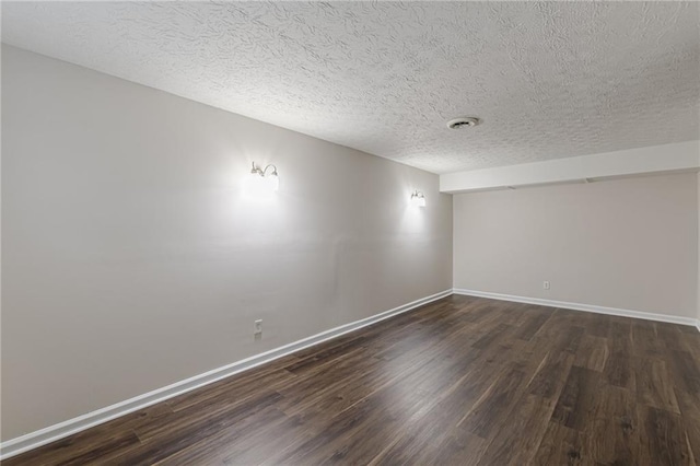 empty room with dark wood-type flooring and a textured ceiling