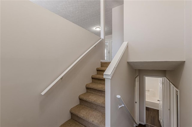 stairway featuring a textured ceiling