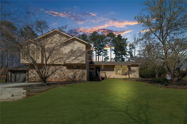 rear view of property with a lawn, driveway, and a garage