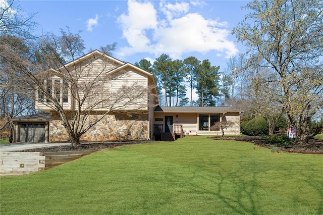 rear view of property with a garage, driveway, and a yard