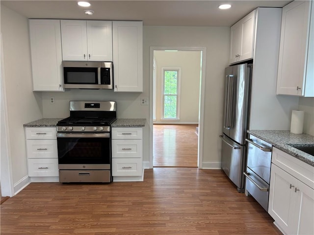 kitchen with white cabinetry, appliances with stainless steel finishes, and wood finished floors