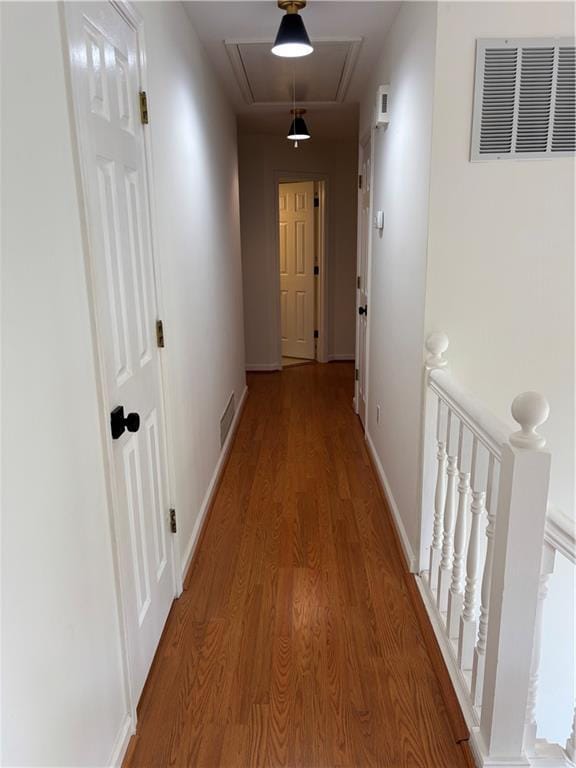 hall featuring visible vents, attic access, baseboards, and wood finished floors