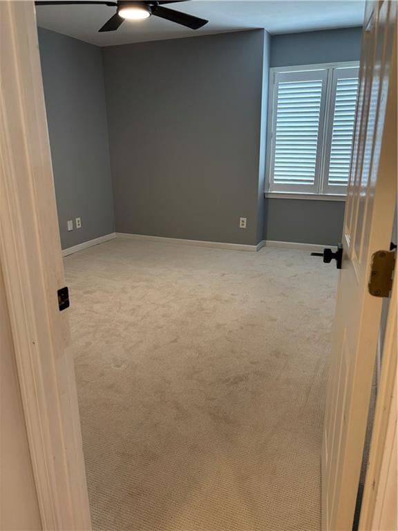 unfurnished room with light colored carpet, baseboards, and ceiling fan