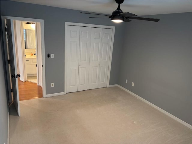 unfurnished bedroom featuring baseboards, ceiling fan, a closet, and light colored carpet