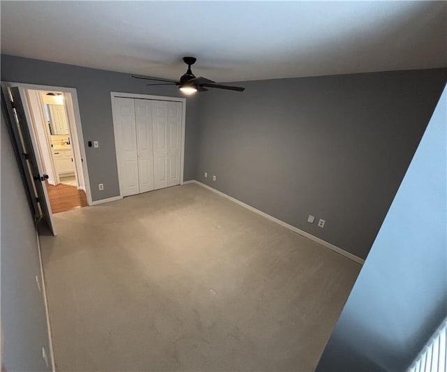 unfurnished bedroom featuring a closet, baseboards, ceiling fan, and light colored carpet