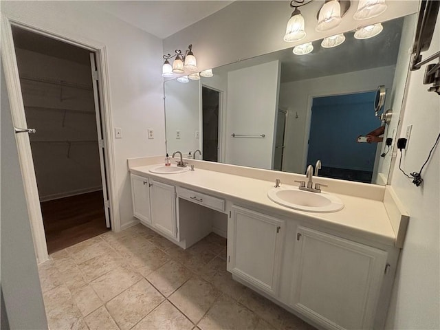 bathroom with double vanity, a sink, baseboards, and a walk in closet