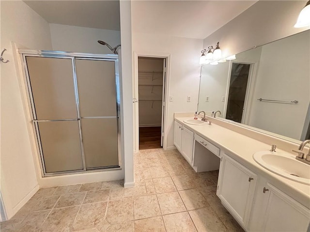 full bathroom with a sink, a walk in closet, a stall shower, and double vanity