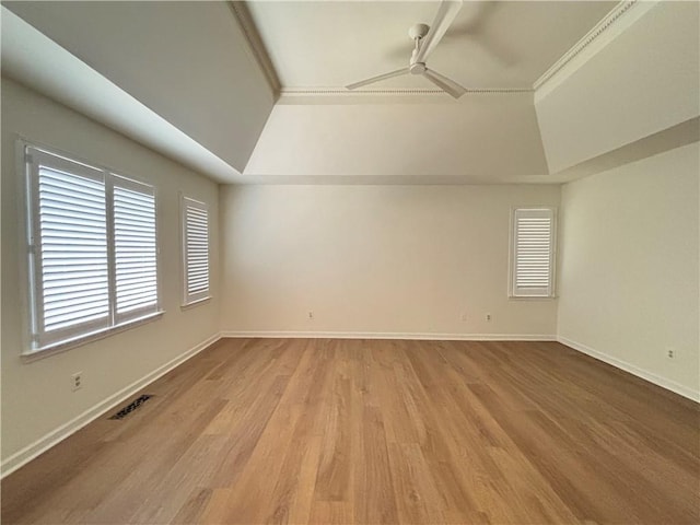 unfurnished room with visible vents, light wood-style floors, baseboards, a raised ceiling, and a ceiling fan