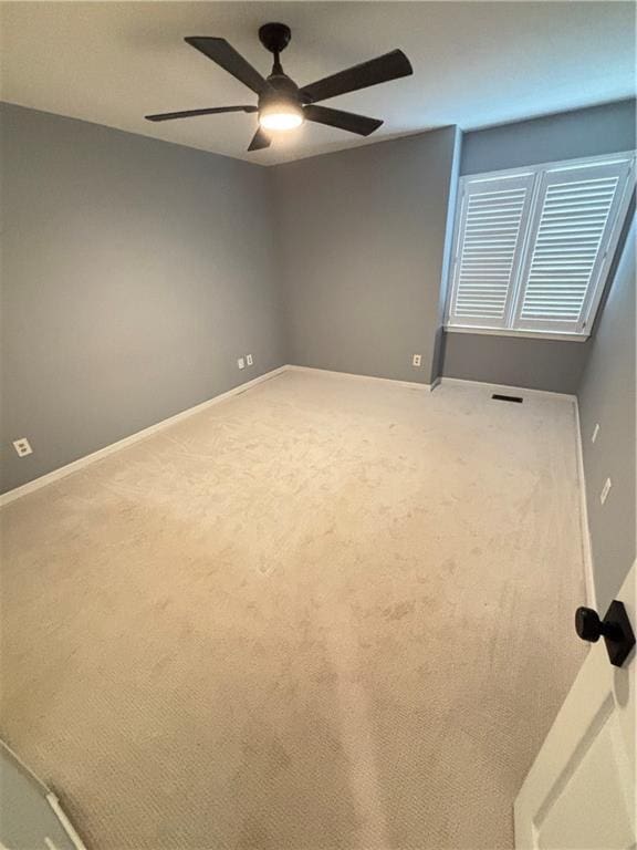 empty room with baseboards, ceiling fan, carpet flooring, and visible vents