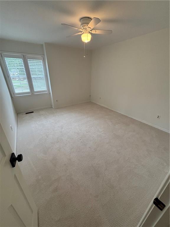 unfurnished room with light colored carpet, a ceiling fan, baseboards, and visible vents