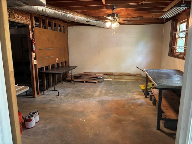 basement with a ceiling fan and concrete block wall