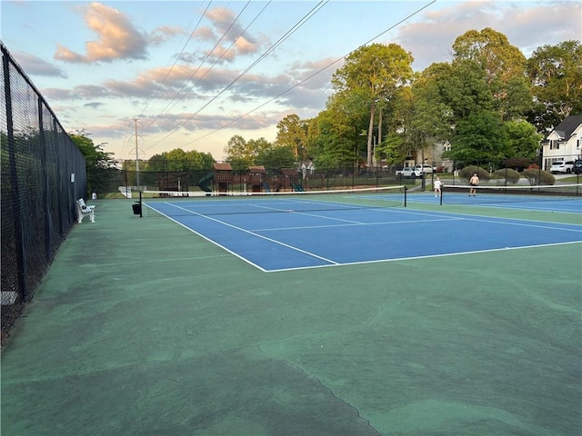 view of tennis court with community basketball court and fence