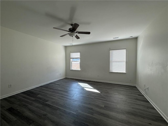 empty room featuring ceiling fan, dark wood-type flooring, visible vents, and baseboards