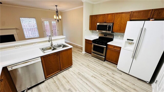 kitchen featuring stainless steel appliances, light hardwood / wood-style flooring, crown molding, and sink