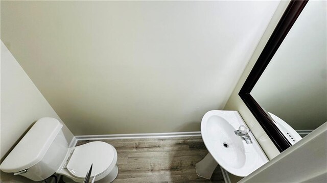 bathroom with wood-type flooring, toilet, and sink