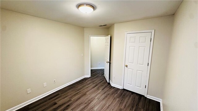 unfurnished room with dark wood-type flooring