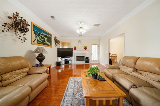 living area with ornamental molding, a fireplace, wood finished floors, and visible vents