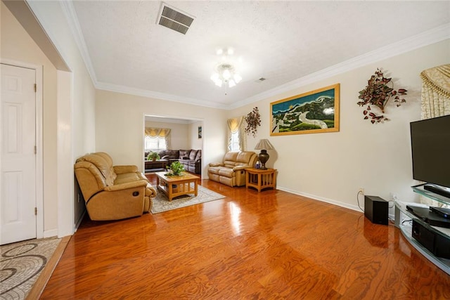 living room featuring ornamental molding, wood finished floors, visible vents, and baseboards