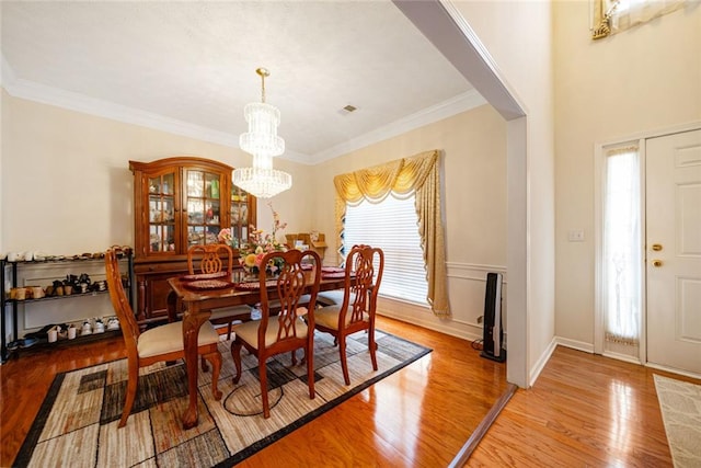 dining area featuring an inviting chandelier, ornamental molding, and light wood finished floors