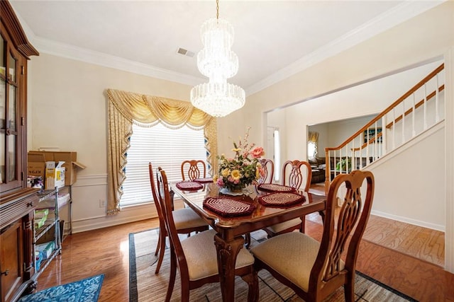 dining room with crown molding, wood finished floors, visible vents, and an inviting chandelier