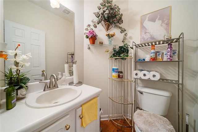 bathroom featuring toilet, visible vents, wood finished floors, and vanity