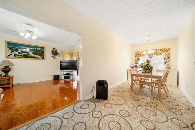 dining area with a notable chandelier, a textured ceiling, baseboards, and wood finished floors