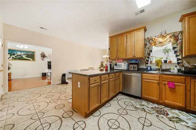 kitchen with visible vents, brown cabinetry, white microwave, a peninsula, and stainless steel dishwasher