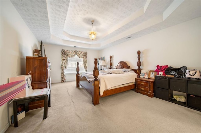 bedroom with a raised ceiling, visible vents, light carpet, a textured ceiling, and baseboards