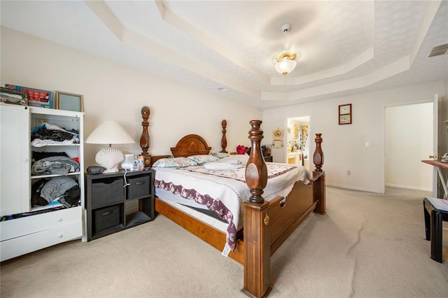 carpeted bedroom featuring a tray ceiling, visible vents, and baseboards