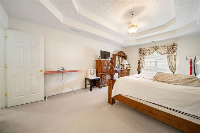 bedroom featuring a textured ceiling, carpet floors, visible vents, baseboards, and a raised ceiling