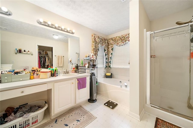 full bathroom featuring a textured ceiling, a stall shower, vanity, and a bath