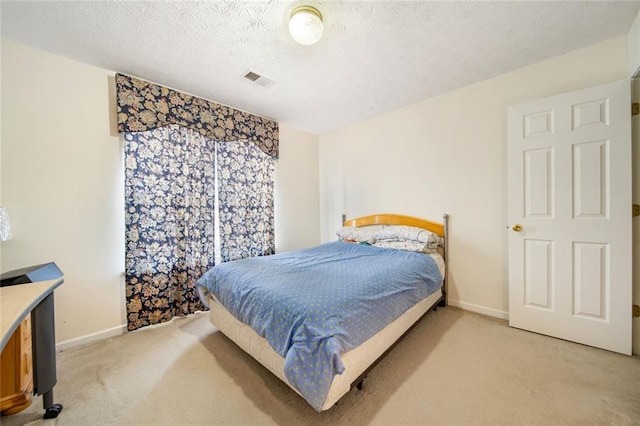 bedroom with baseboards, visible vents, a textured ceiling, and light colored carpet