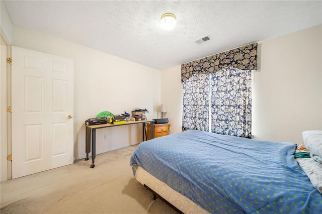 bedroom featuring carpet floors, visible vents, and a textured ceiling