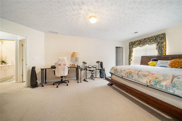 carpeted bedroom featuring a textured ceiling, visible vents, and ensuite bathroom