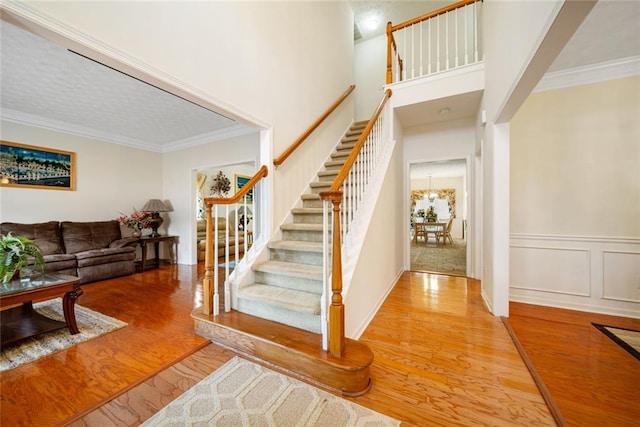 stairs featuring a wainscoted wall, crown molding, a decorative wall, and wood finished floors