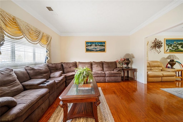 living room with ornamental molding, visible vents, and wood finished floors