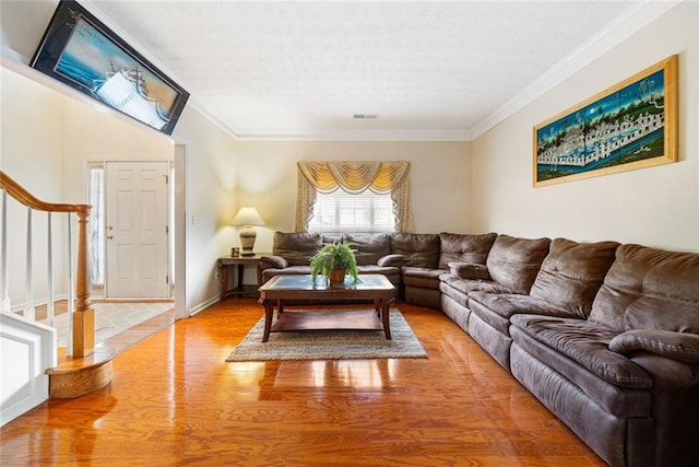 living room featuring ornamental molding, visible vents, stairway, and light wood finished floors