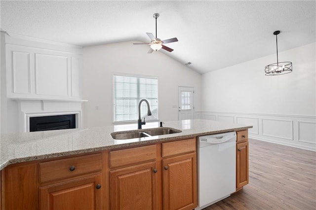 kitchen with light stone countertops, sink, white dishwasher, pendant lighting, and light wood-type flooring