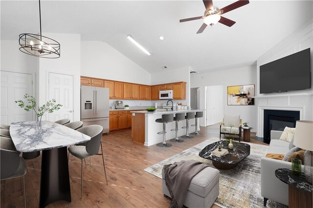 unfurnished living room featuring hardwood / wood-style floors, a large fireplace, vaulted ceiling, and ceiling fan