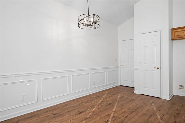 unfurnished dining area featuring dark hardwood / wood-style floors, vaulted ceiling, and a notable chandelier