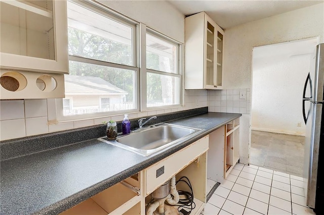3221 Colquitt Dr, Atlanta, GA 30340 - kitchen featuring dark countertops, a sink, light tile patterned floors, freestanding refrigerator, and glass insert cabinets