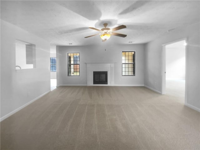 unfurnished living room with baseboards, light colored carpet, a healthy amount of sunlight, and a fireplace