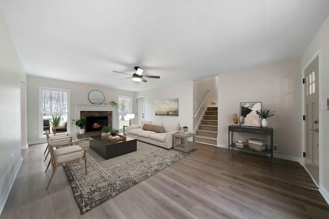 living room with ceiling fan, wood finished floors, a high end fireplace, baseboards, and stairway