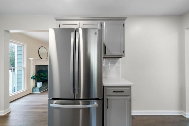 kitchen featuring gray cabinets, light countertops, decorative backsplash, freestanding refrigerator, and wood finished floors