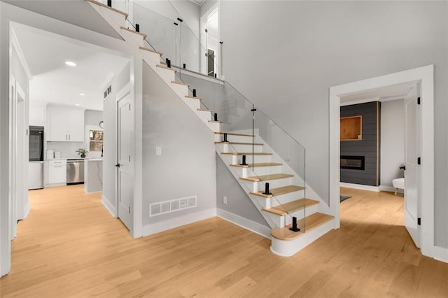 270 Boulder Dr, Roswell, GA 30075 - staircase featuring wood finished floors, a large fireplace, baseboards, a towering ceiling, and recessed lighting