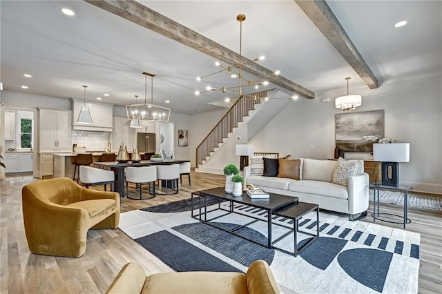 living room featuring beam ceiling, light hardwood / wood-style floors, and a notable chandelier