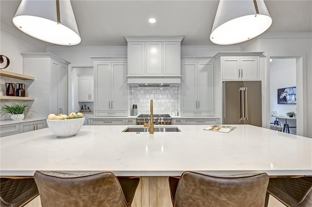 kitchen featuring a large island, a breakfast bar, high end fridge, and decorative light fixtures