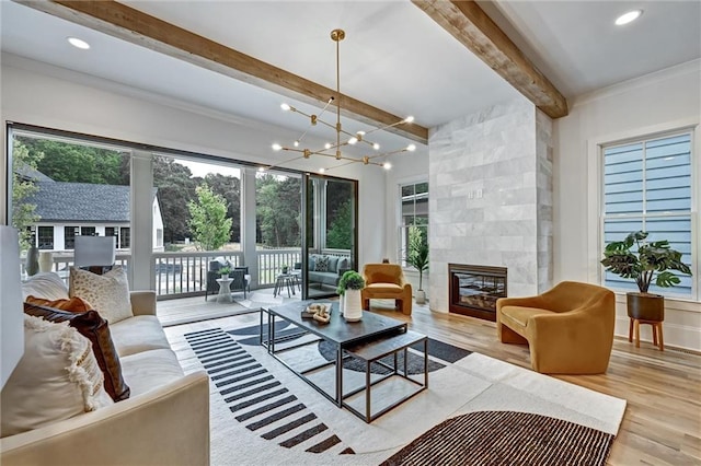 living room with plenty of natural light, a chandelier, and a tiled fireplace