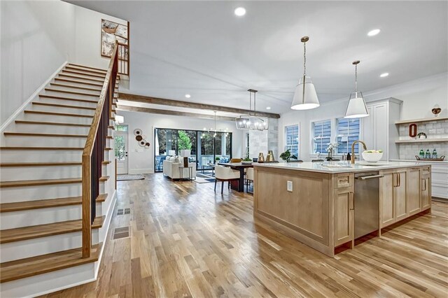 kitchen with an inviting chandelier, a center island with sink, hanging light fixtures, stainless steel dishwasher, and light wood-type flooring