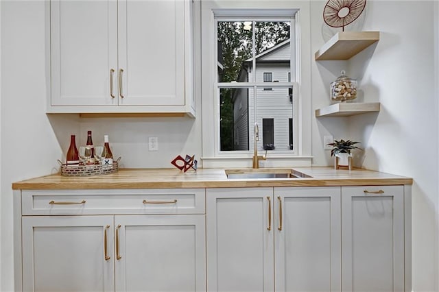 bar with white cabinetry and sink